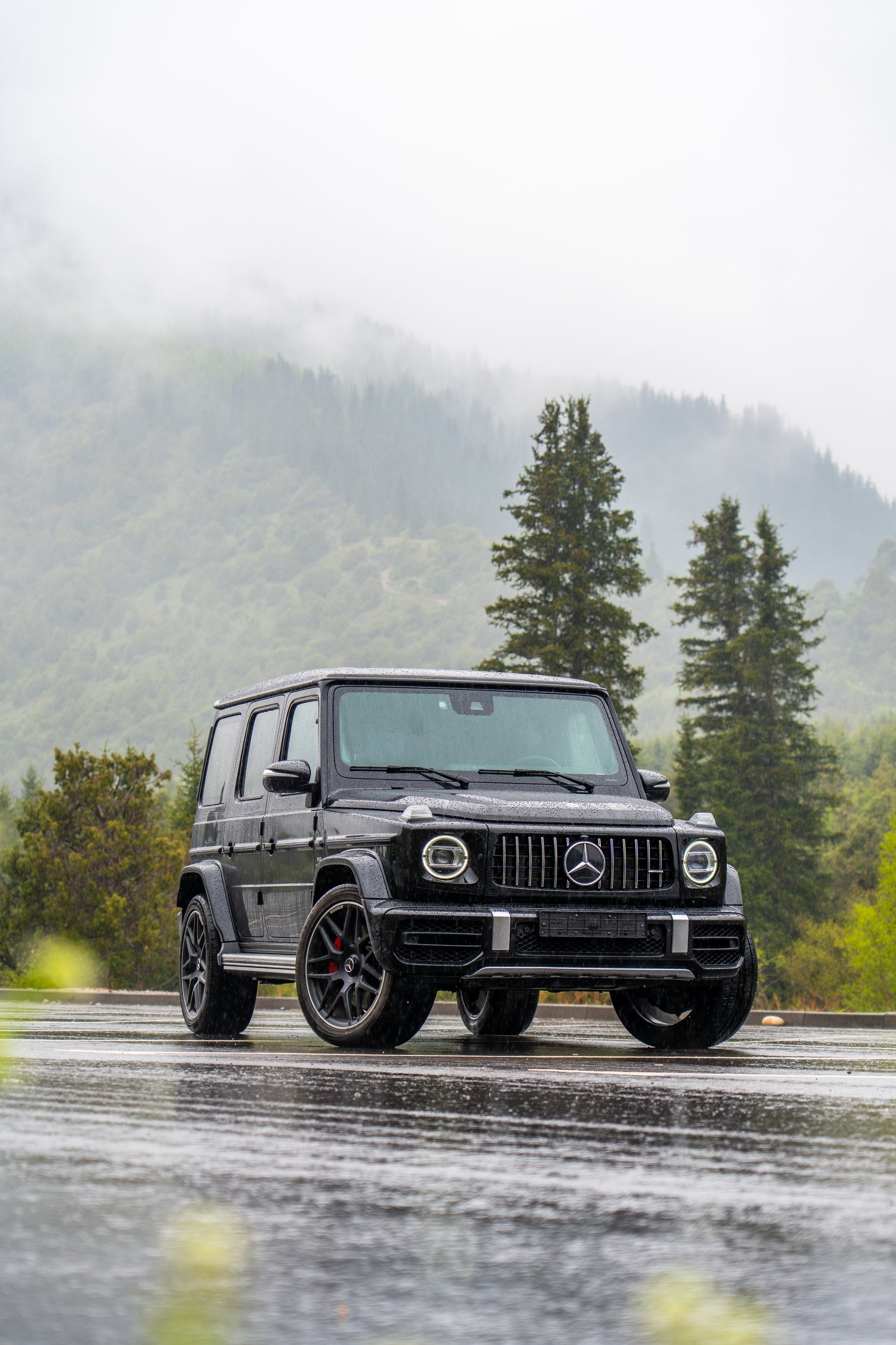 Bishkek, Kyrgyzstan - May 12, 2024: Black Mercedes G-Wagon on a rainy day in a mountain setting