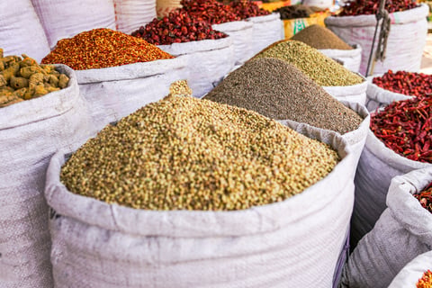 A vibrant display of spices including dried chilies, turmeric, cumin and coriander arranged in sacks at a market stall