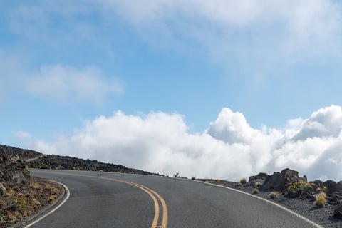 Mountain road above the clouds with scenic views and soft light stretching across alpine peaks