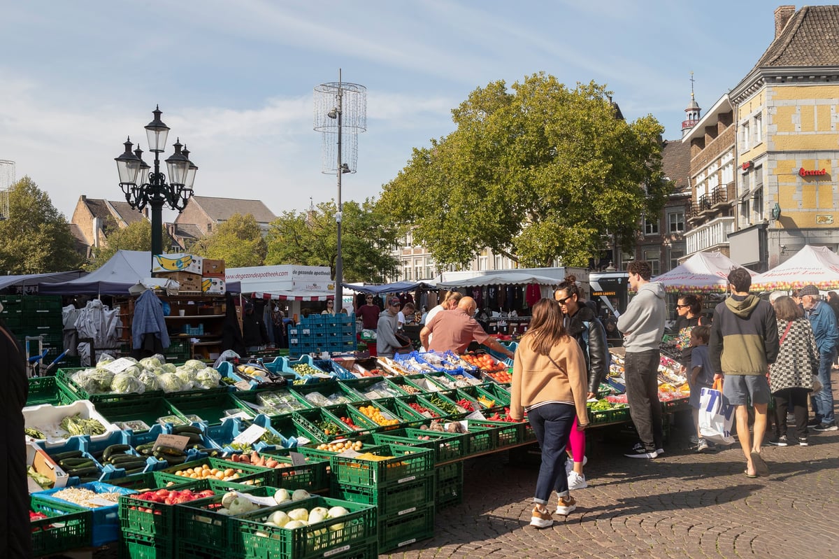 Bucharest food market with a fruit and vegetable stall of fresh seasonal produce and people shopping at market stalls