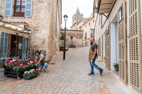 Florists arranging potted flowers outside their small business on a picturesque old-world street