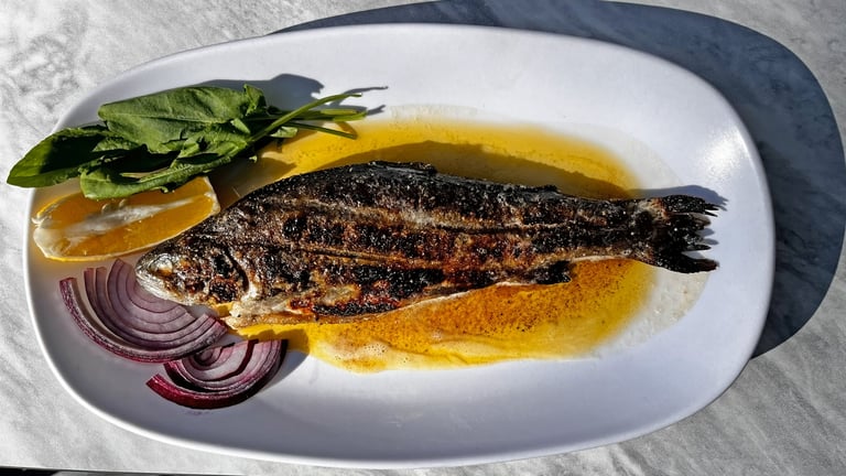 Grilled whole trout served on a plate with fresh greens and lemon