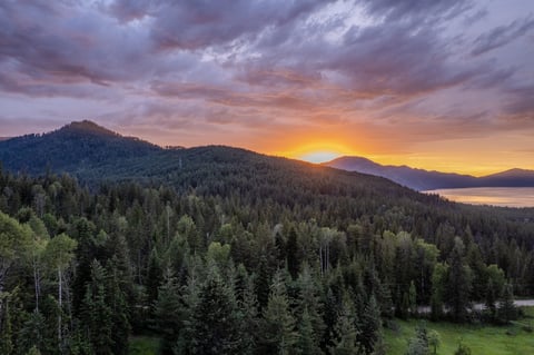 Aerial view of a lake and national forest at sunset after a storm, with dramatic golden light