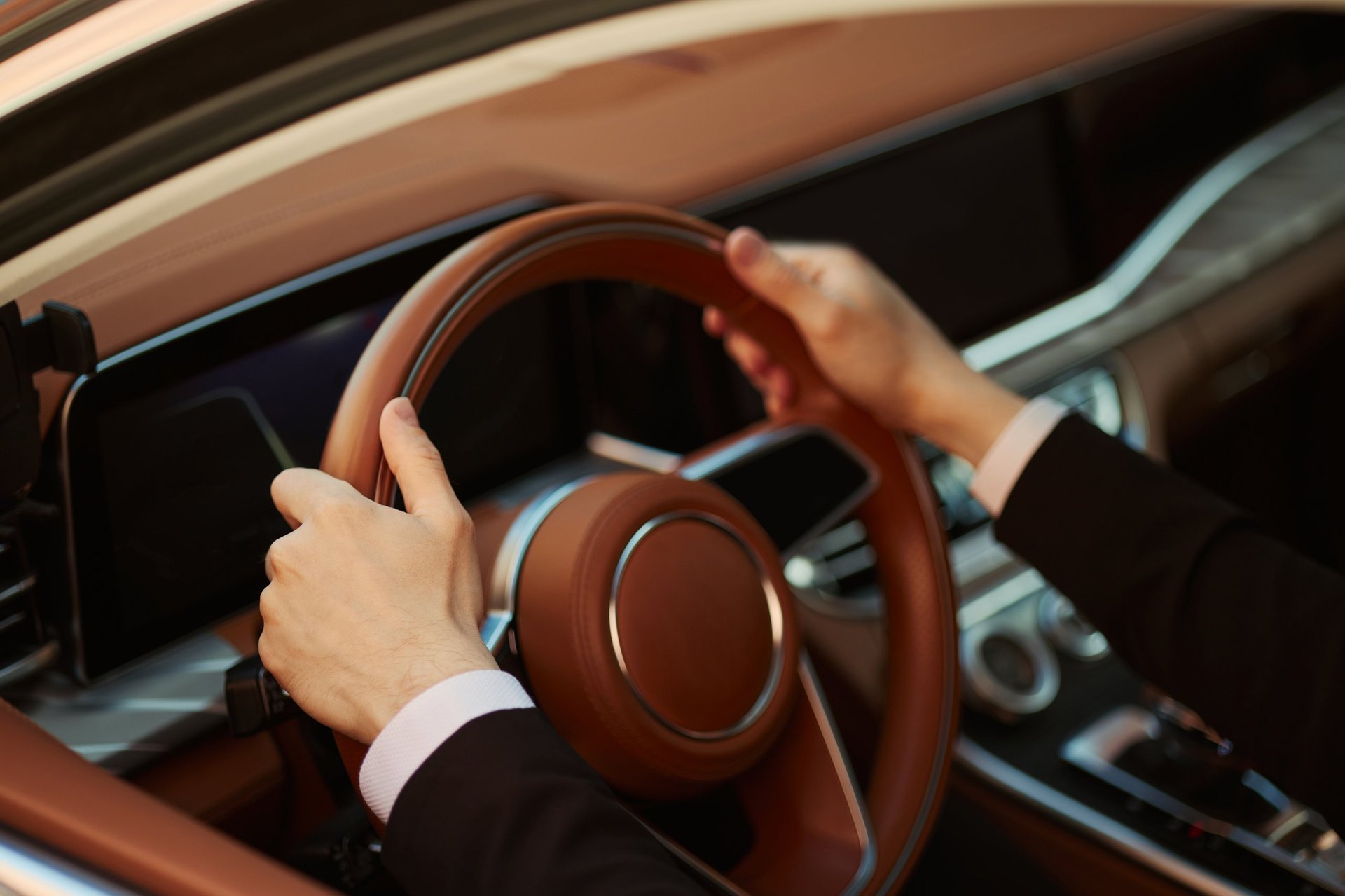 Close-up of a young adult driver's hands gripping the steering wheel while driving a modern car