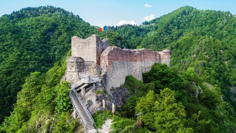 Medieval fortress ruins on a rocky hilltop under blue sky