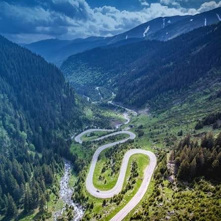 Aerial view of winding mountain road with sharp hairpin curves through alpine landscape