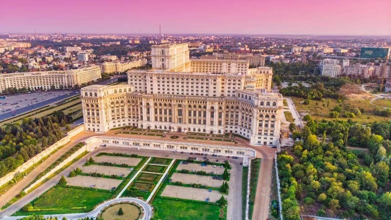 Aerial view of the Palace of Parliament and surrounding cityscape at sunset in Bucharest