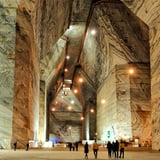 Large underground cavern with soaring stone walls, ambient lighting, and visitors walking through the spacious cave gallery