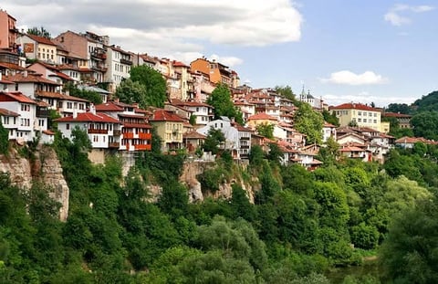 Hillside village with colorful houses built on steep green slopes overlooking a forested valley