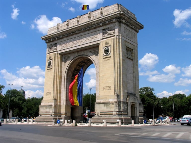 Triumphal arch monument with Romanian flag in Bucharest city square on sunny day