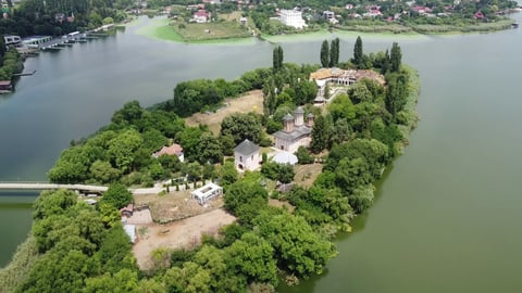 Aerial view of a large estate on a tree-lined peninsula surrounded by water, with manicured grounds and multiple buildings.