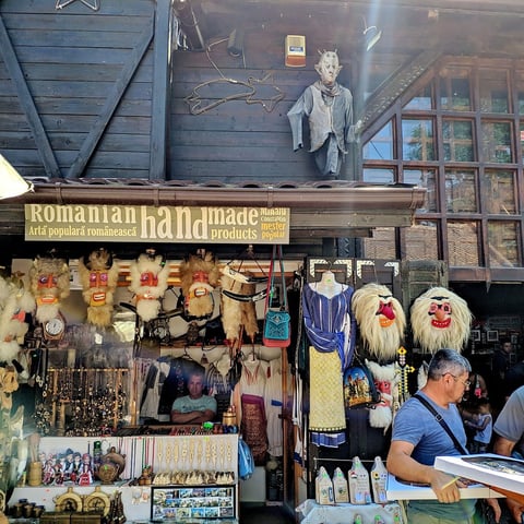Rustic souvenir shop storefront displaying wooden masks, crafts, and traditional Romanian handmade products with vendor inside