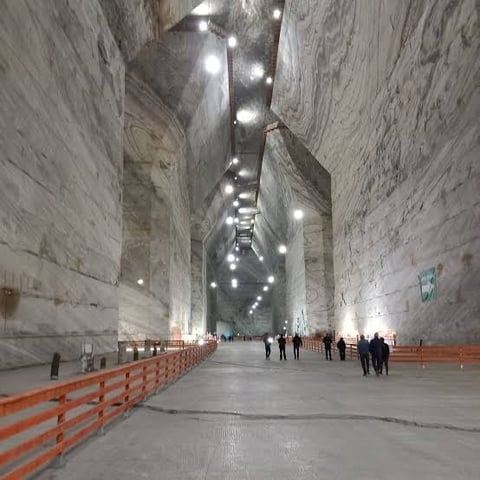 Underground tunnel with concrete walls, overhead lighting, and orange safety barriers lining the sides